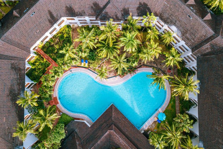 Aerial view of Diani Reef's kidney-shaped main swimming pool surrounded by palm trees