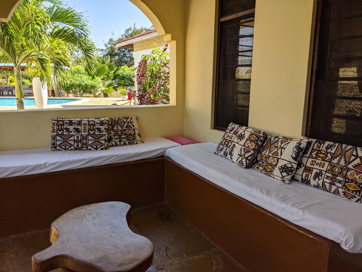 Covered veranda lounge seating overlooking the pool at Shalom Cottages