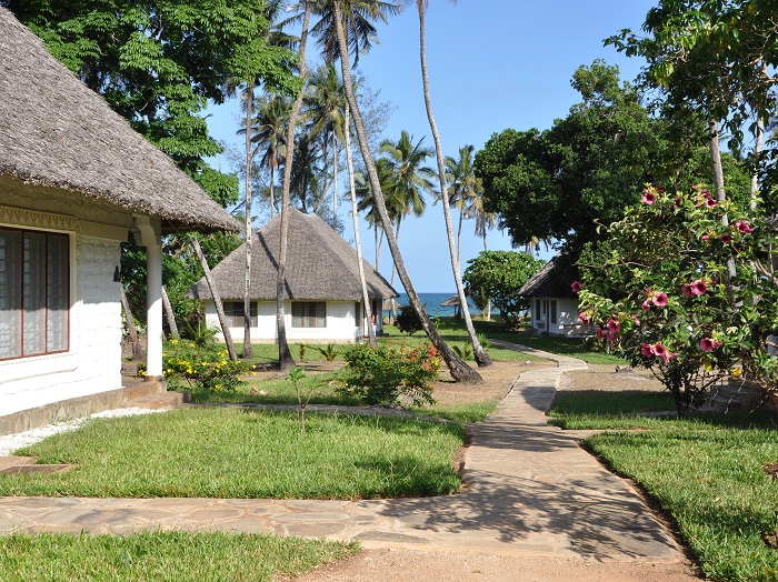 Thatched-roof cottages with pathway leading toward the beach at Simba+Oryx